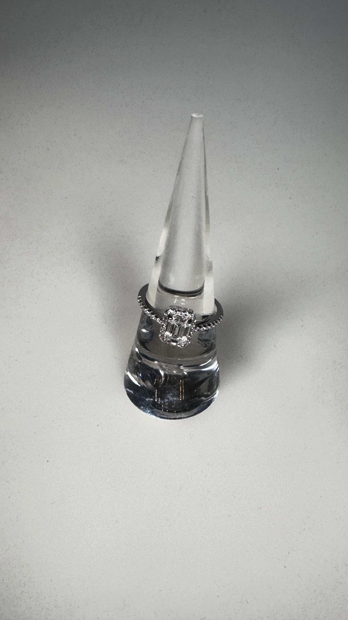 Emerald cut lab grown moissanite ring on clear display cone, white background