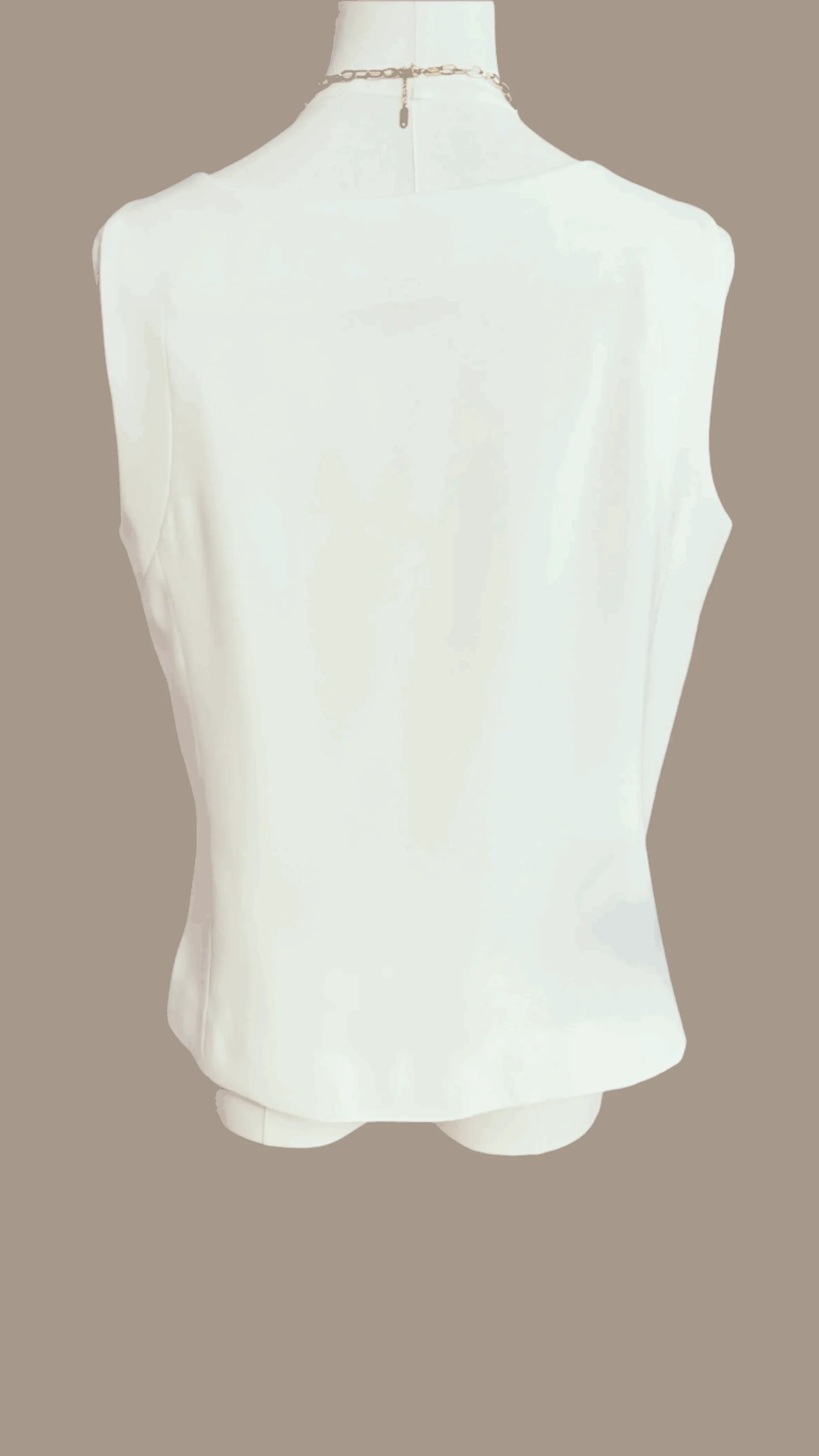 Back view of sleeveless white blouse on mannequin against beige background