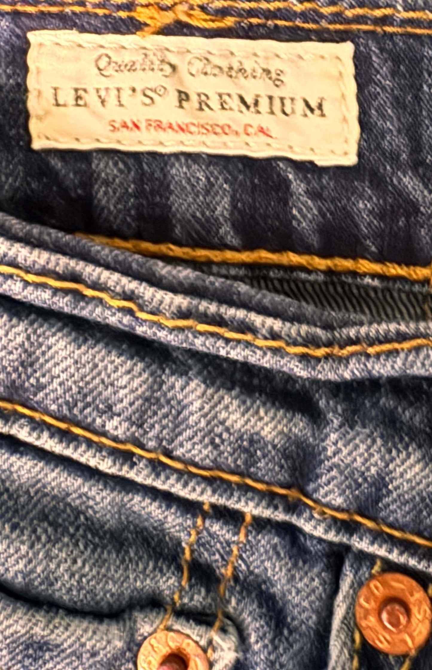 Levi's Premium jeans label on blue denim with yellow stitching and metal rivets detail.