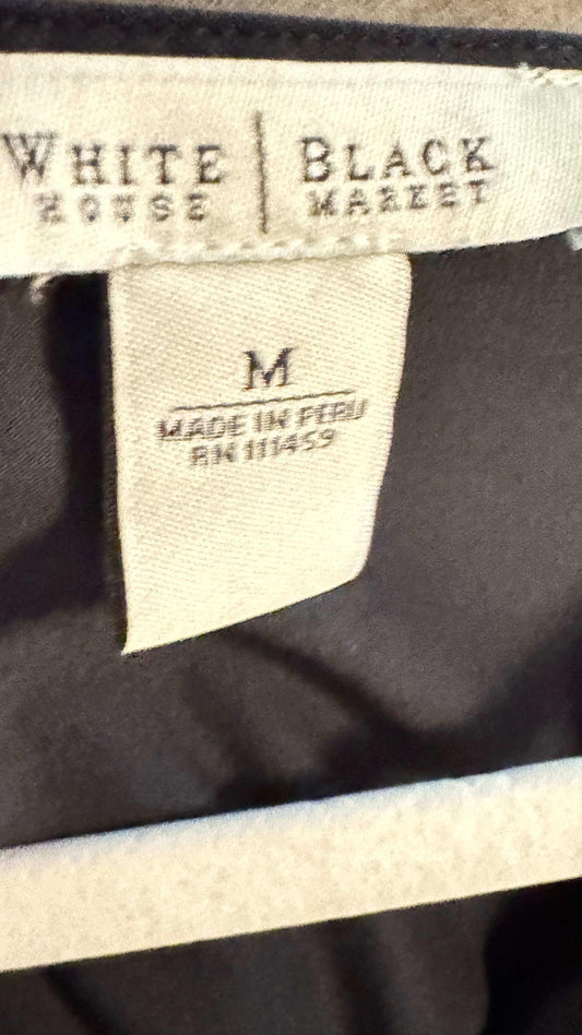 White House Black Market blouse clothing tag, size M, made in Peru, on dark fabric
