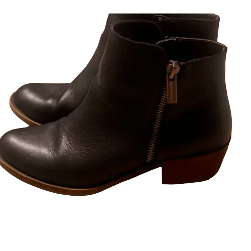 Black leather ankle boots with side zipper and brown sole on white background