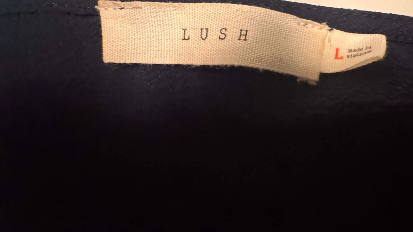 LUSH brand beige clothing tag on blue blouse, size large, made in Vietnam