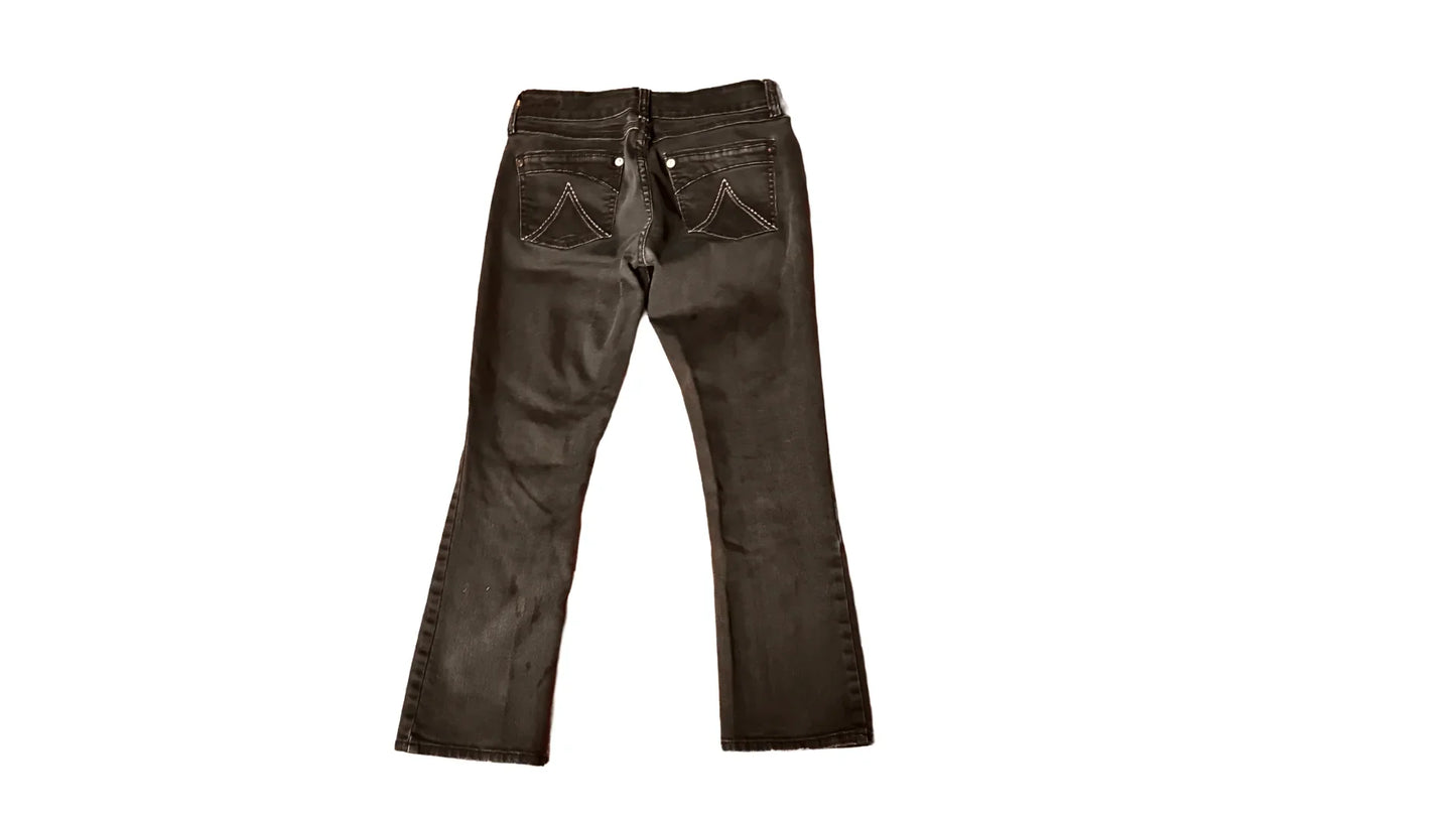 Black denim jeans with back pockets and white stitching on a white background