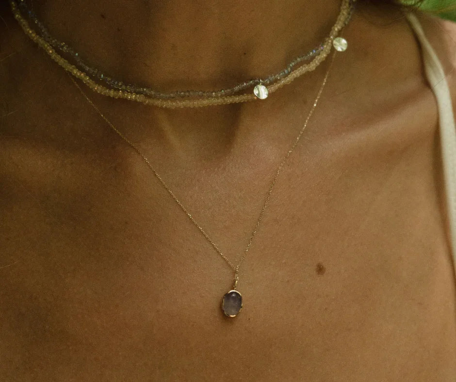 Layered beaded choker necklace with pearls and gold chain pendant on woman's neck