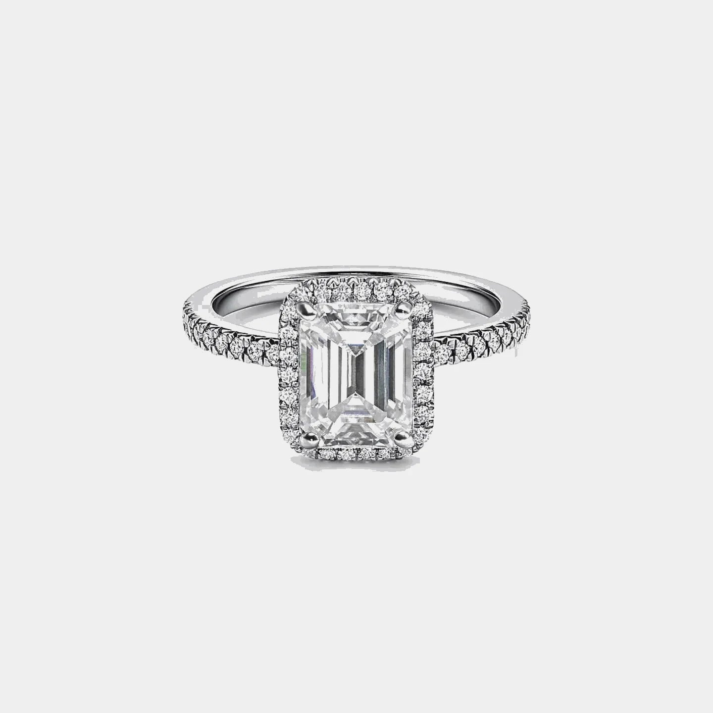 emerald cut moissanite ring with pavé band on white background