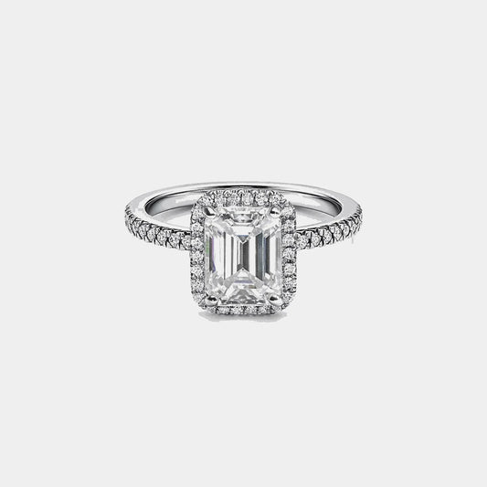 emerald cut moissanite ring with pavé band on white background
