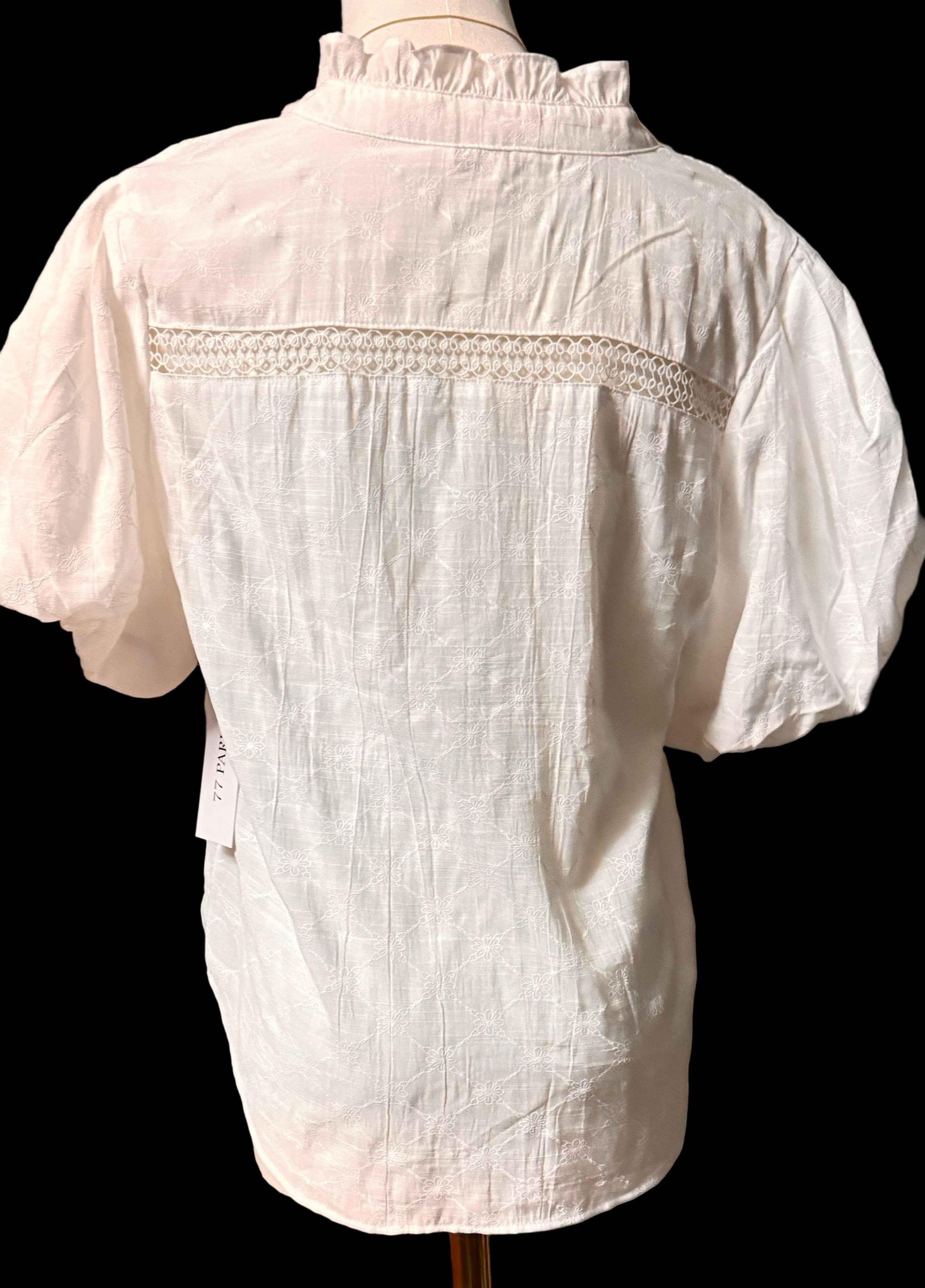 White blouse with puff sleeves, lace detail, and ruffled collar on mannequin