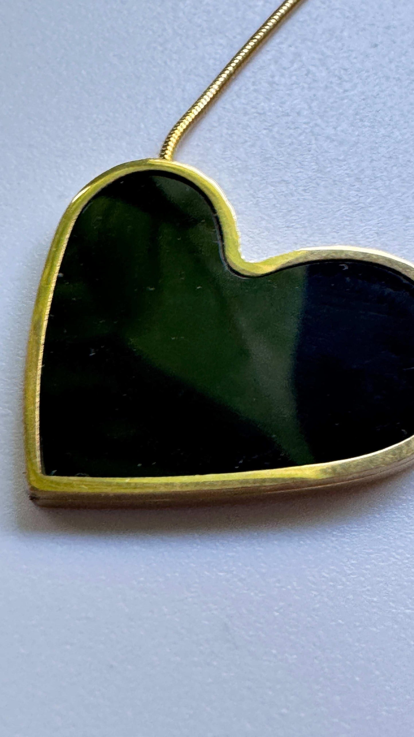 Black heart pendant necklace with gold trim on light background