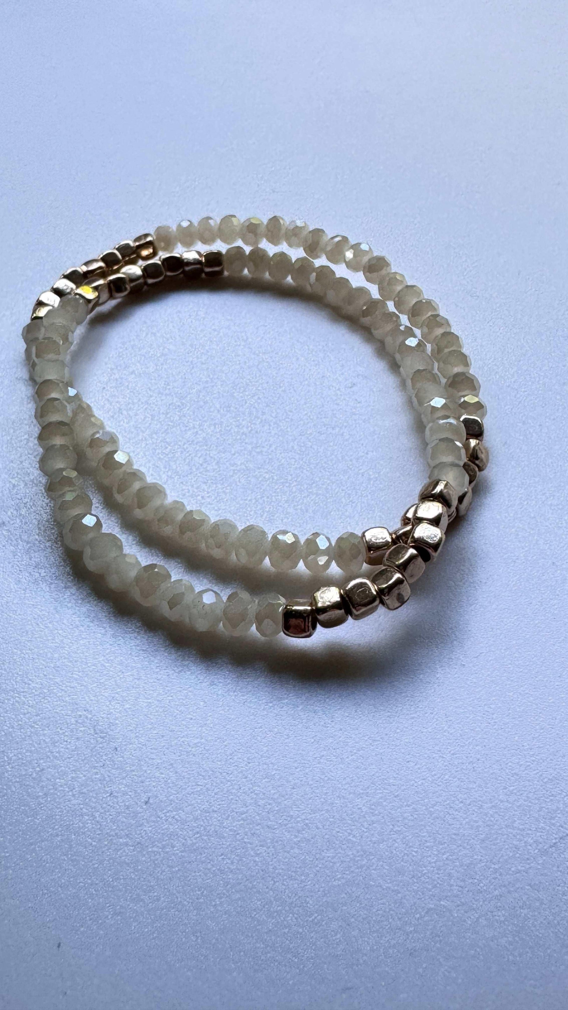 Beige beaded bracelet with metallic accents on a light textured surface