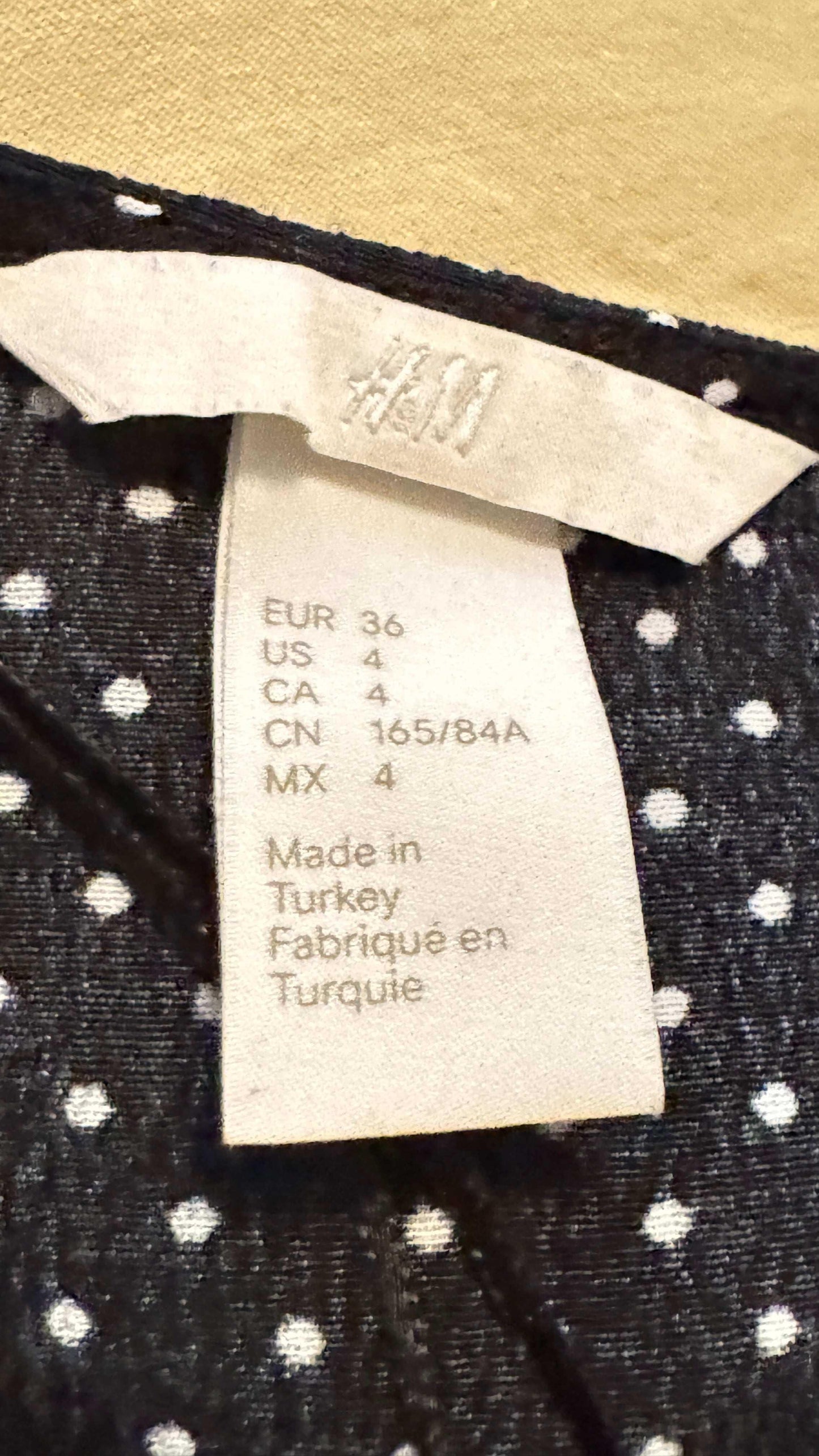 H&M clothing label on black and white polka dot blouse showing size and made in Turkey