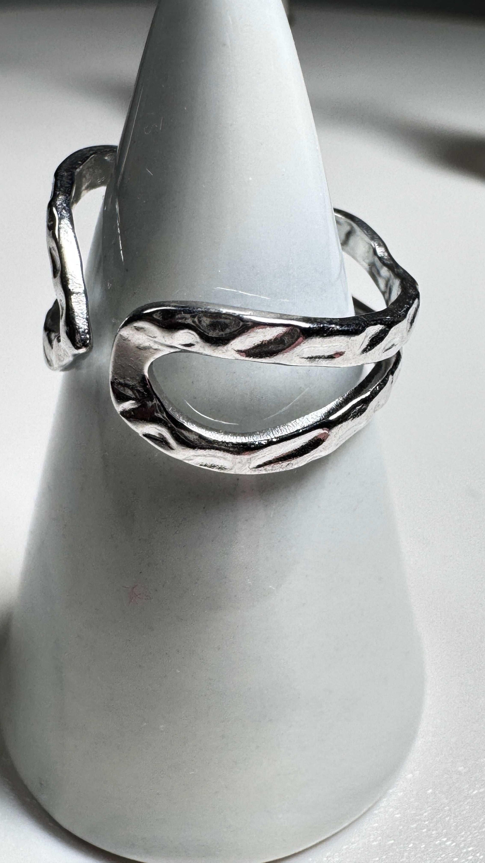 Hammered open sterling silver ring with textured finish on white cone display