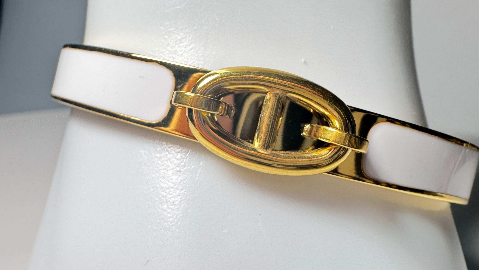 Luxury gold clasp bracelet with white enamel on a display, stainless steel, 18K gold plating