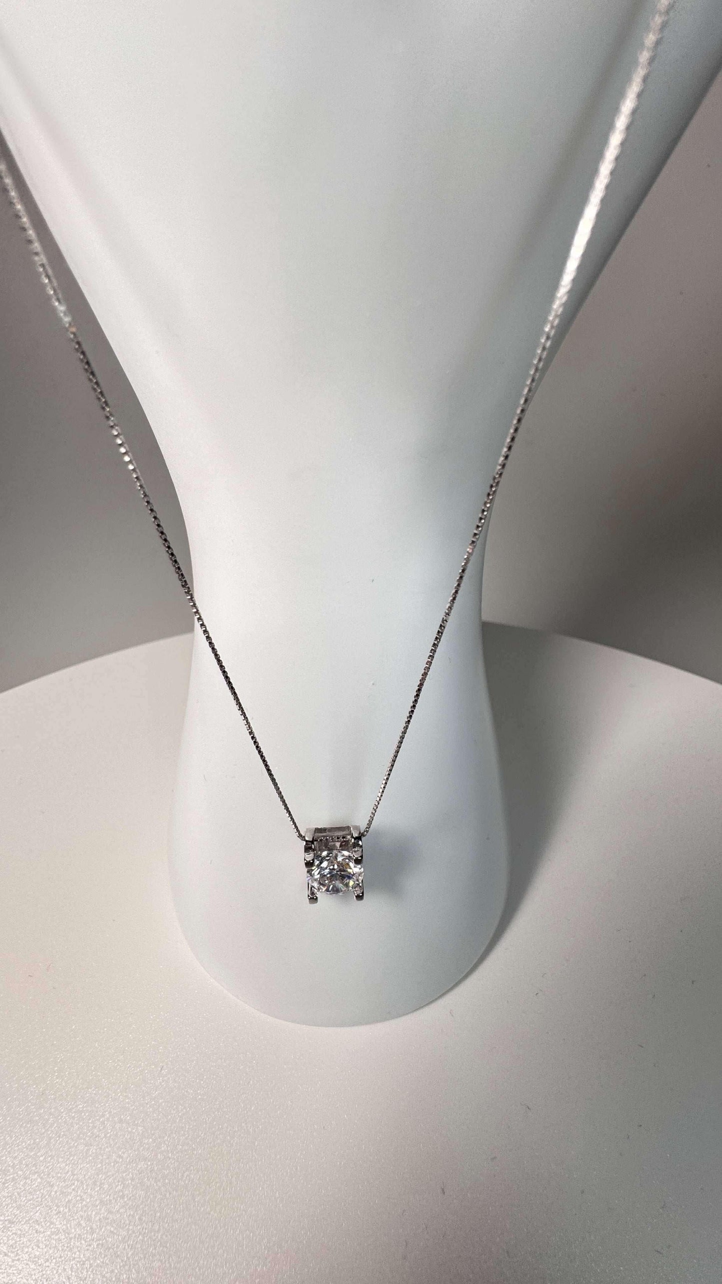Silver moissanite solitaire pendant necklace on white display bust