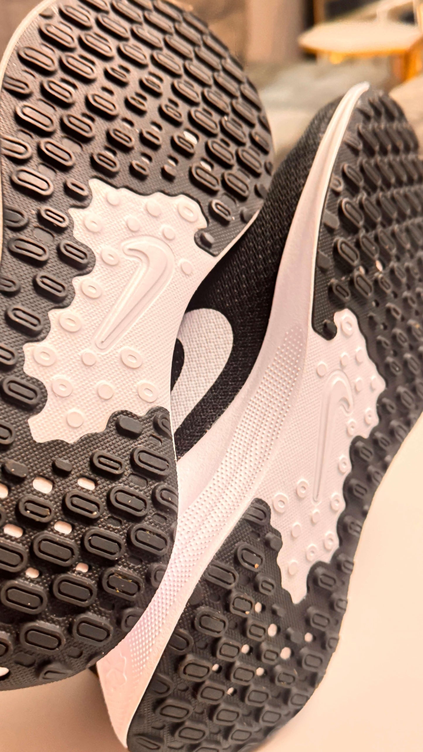 Close-up of black and white Nike shoe soles with textured grip pattern and Swoosh logo