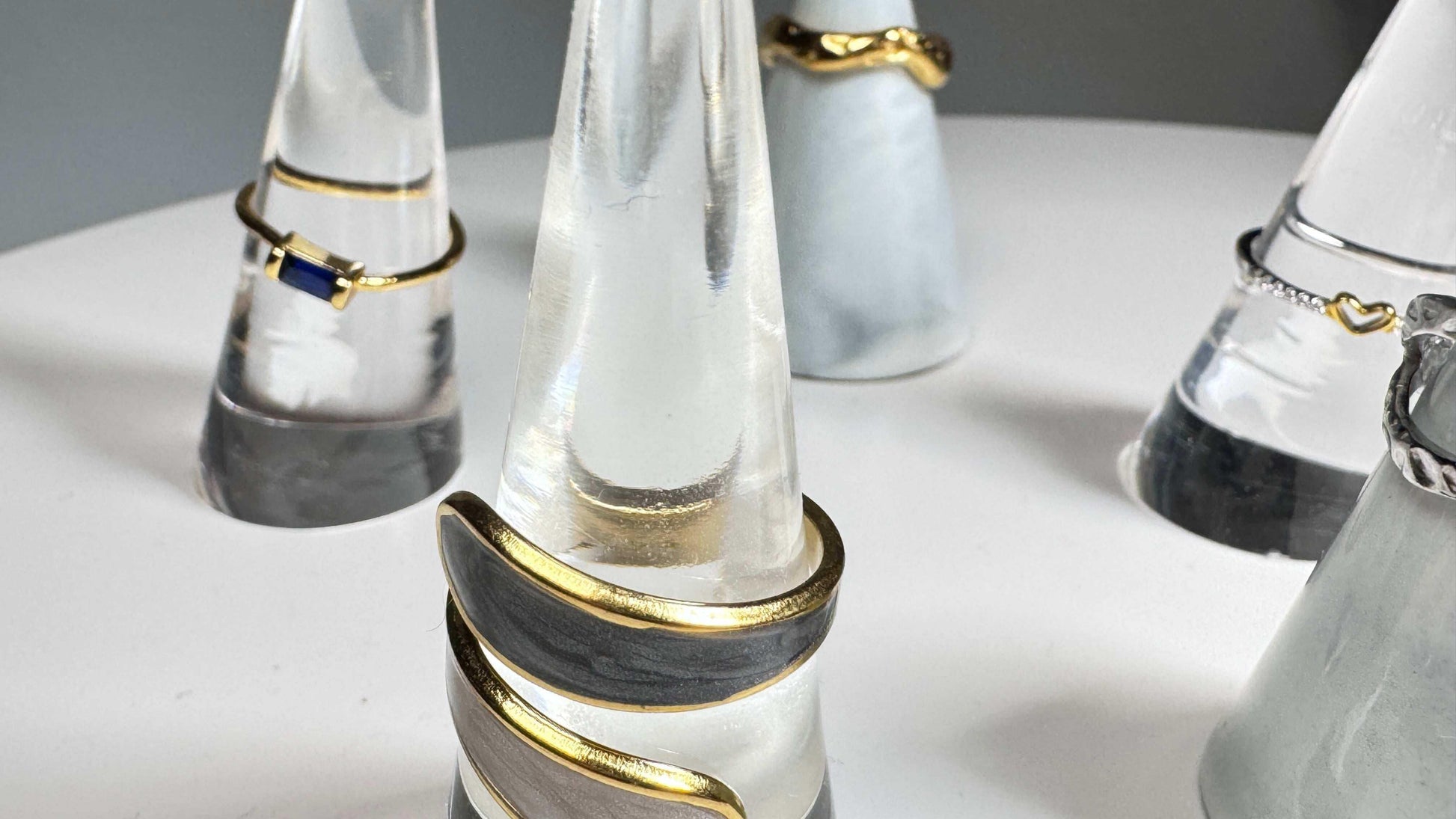 Open natural stone ring with gold accents on marble display, modern minimalist jewelry