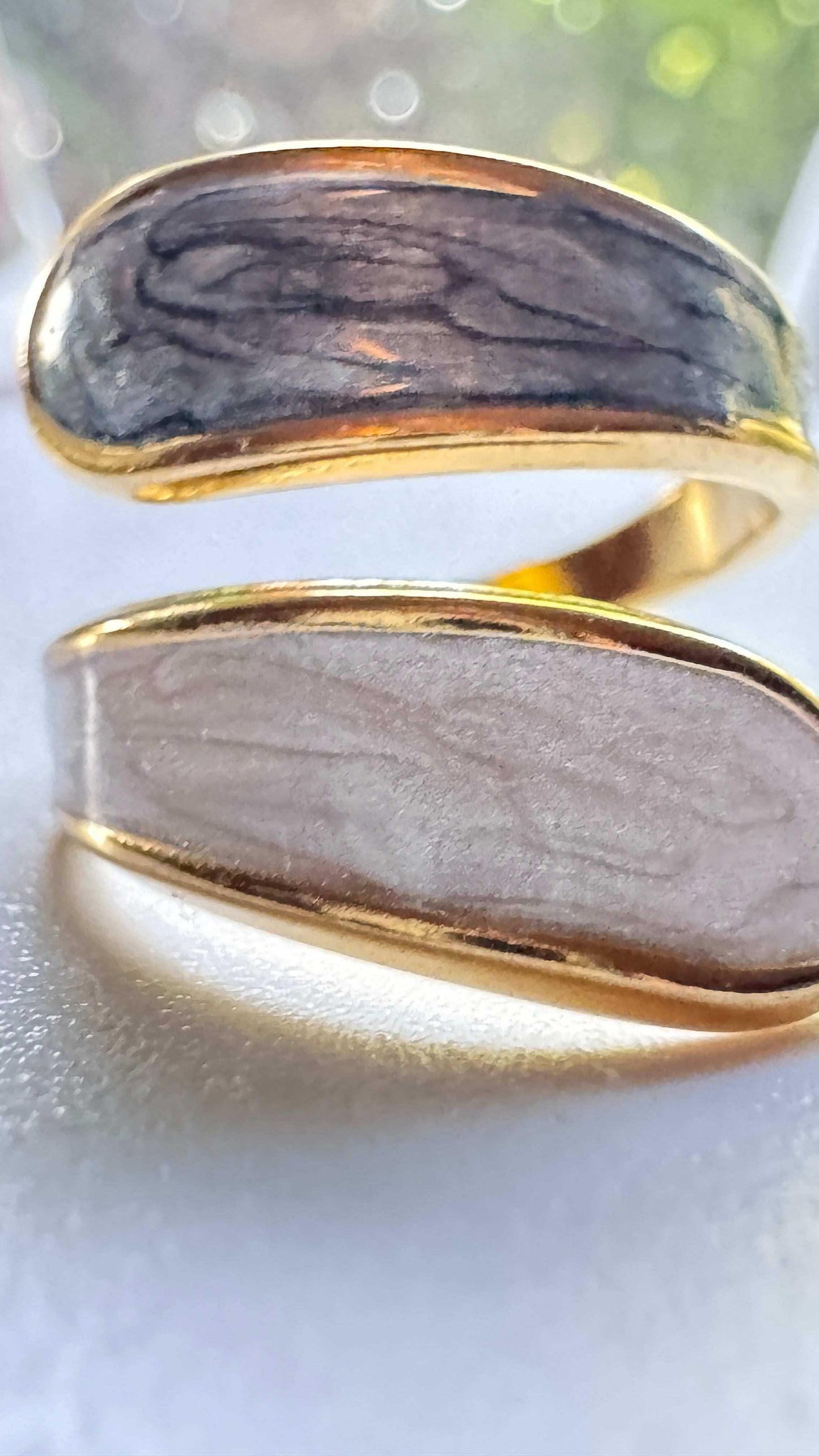 Gold open ring with natural stone inlay, close-up on textured white surface