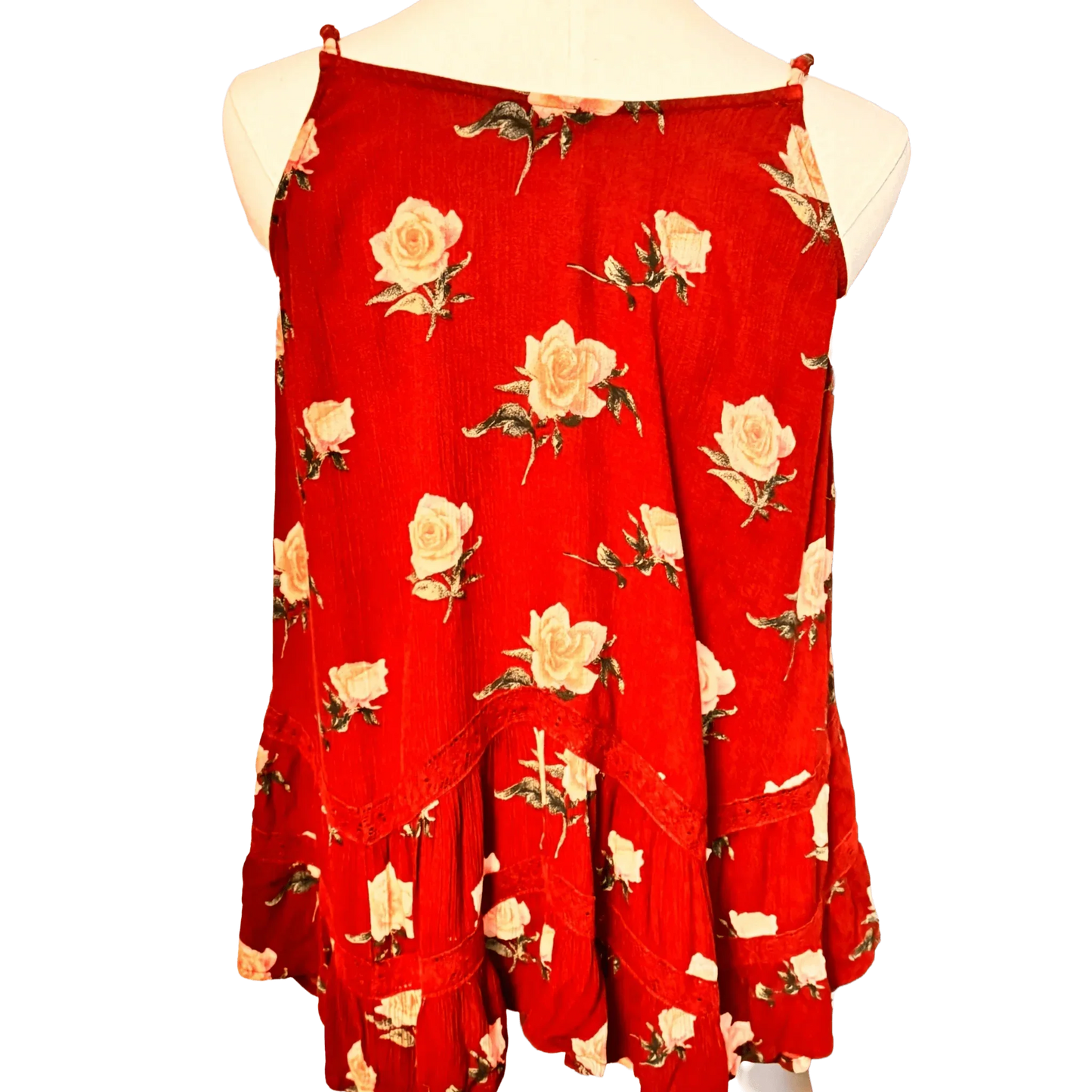 Red sleeveless floral top with white rose print and ruffled hem on mannequin
