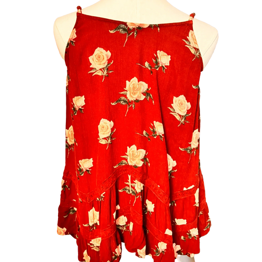 Red sleeveless floral top with white rose print and ruffled hem on mannequin