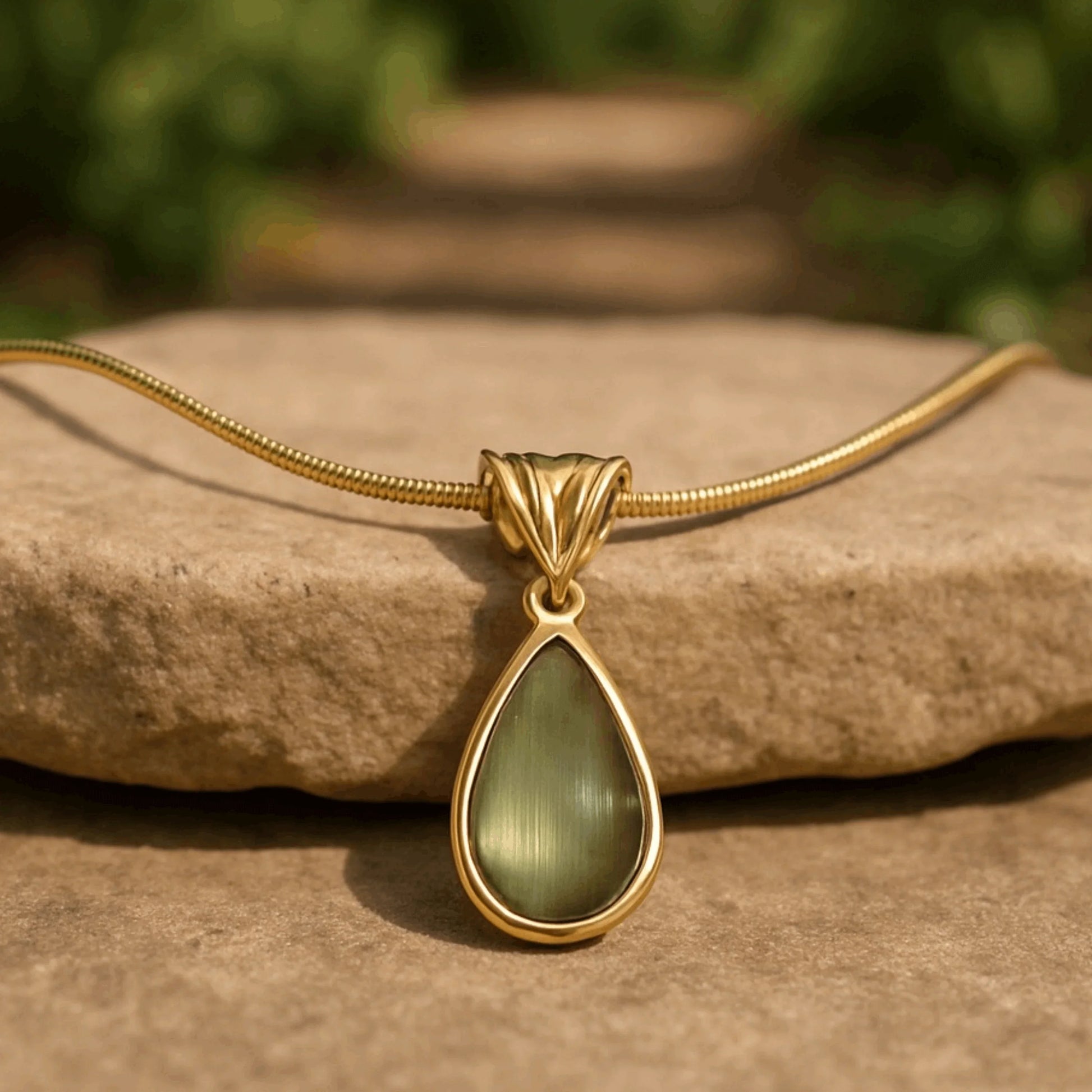 Teardrop green glass necklace with gold stainless steel chain on stone surface