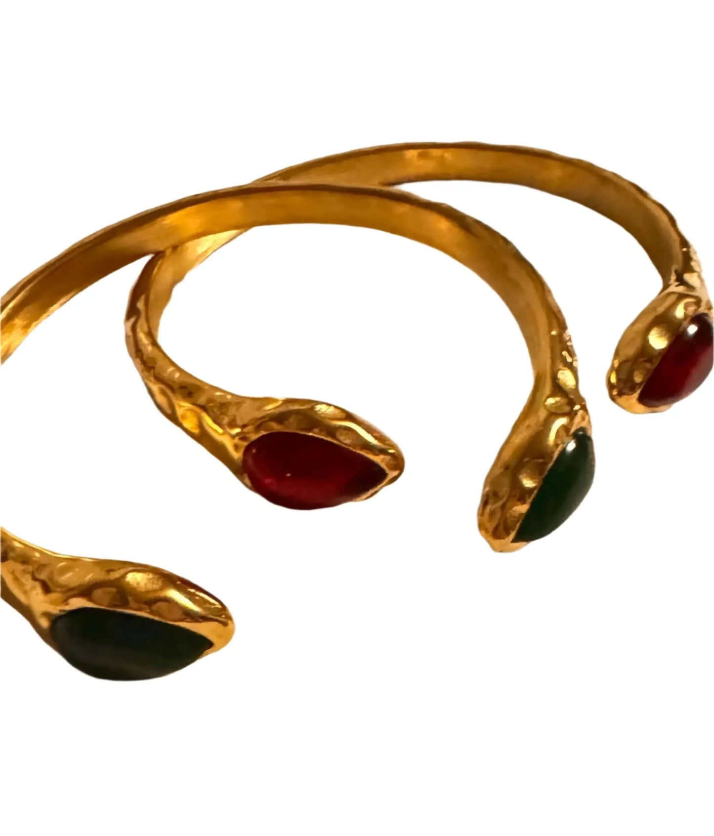 Gold hammered bracelets with red and green gem ends on white background