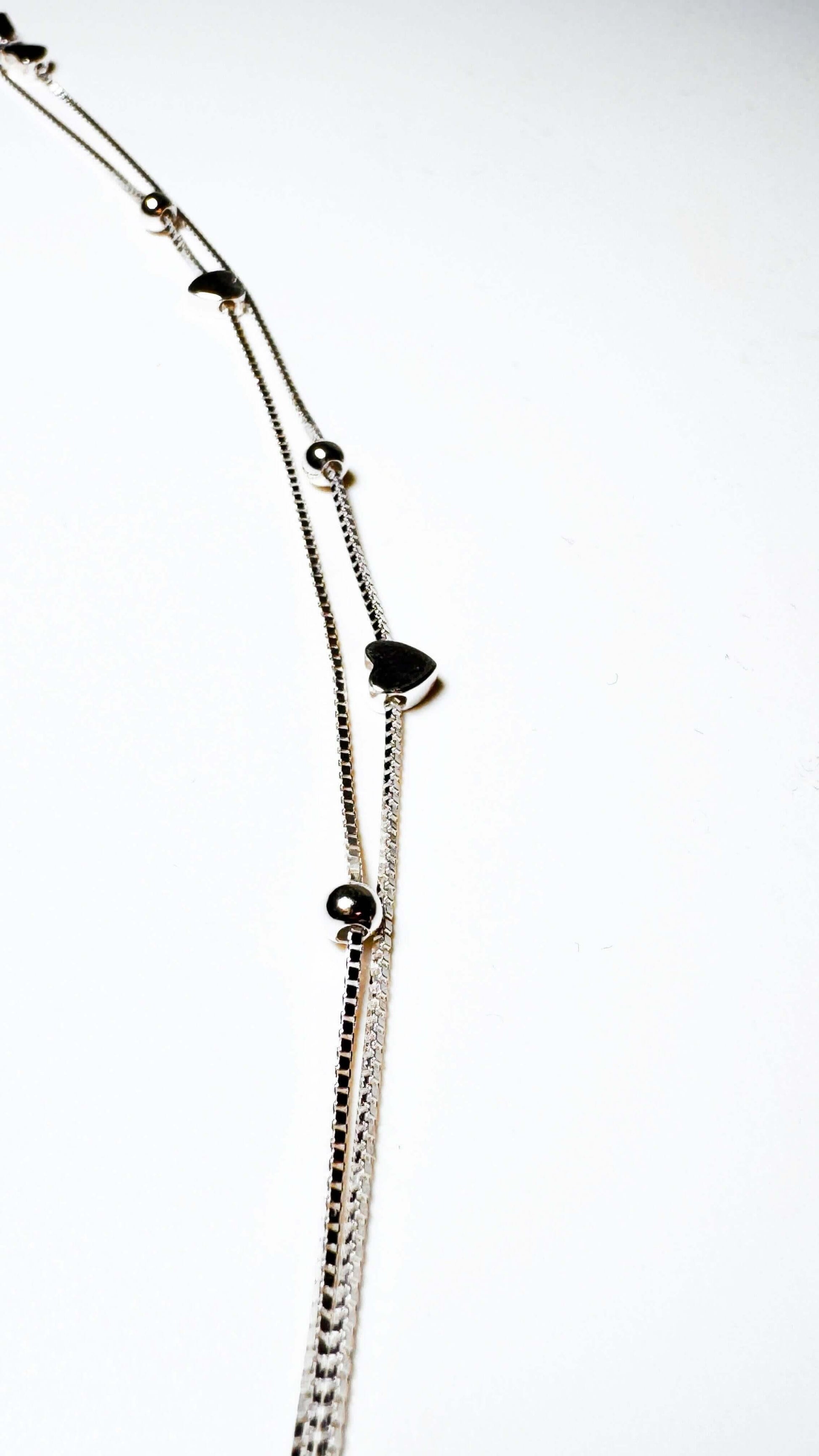 Silver bracelet with heart and bead charms on white background