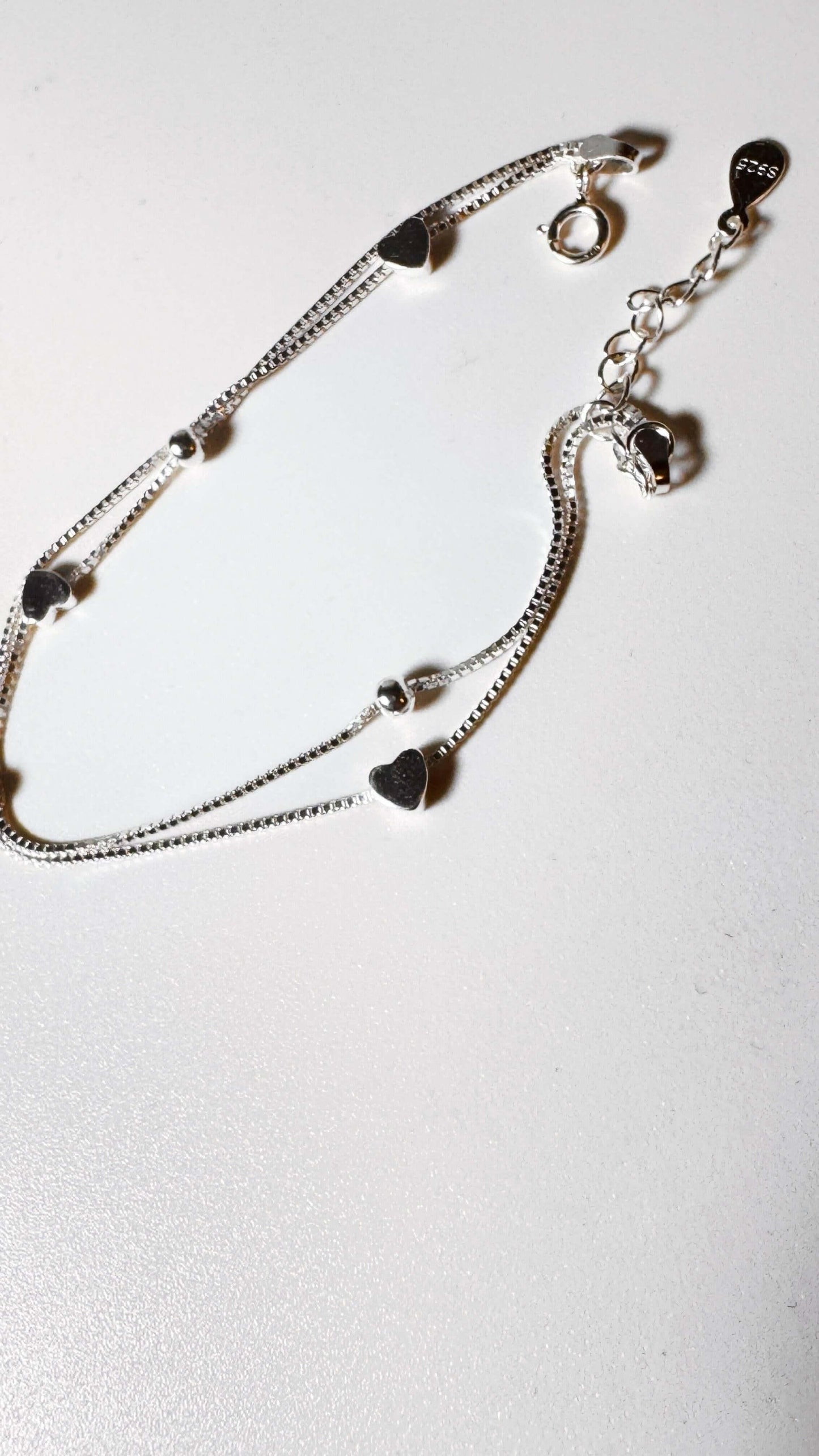 Sterling silver double chain bracelet with heart charms on white background