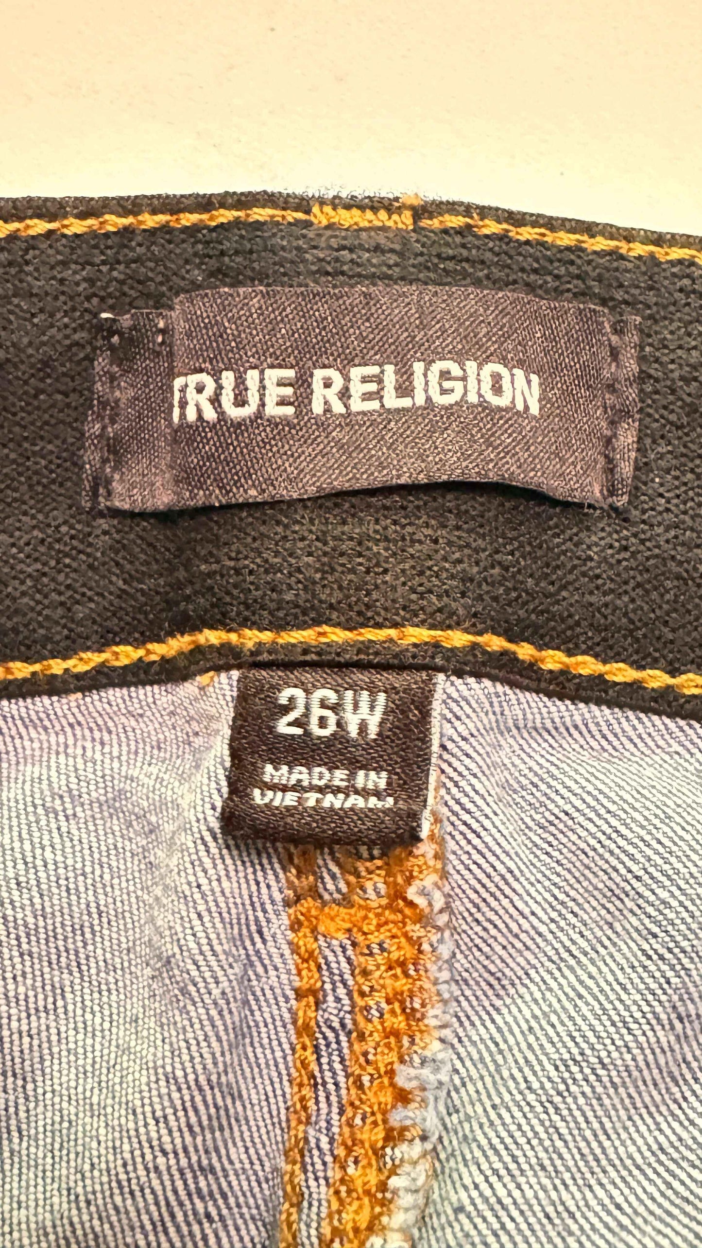 True Religion denim jean tags, size 26W, made in Vietnam with visible orange stitching