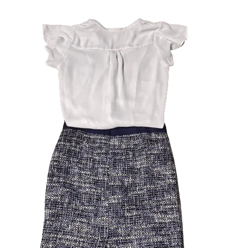 White ruffle sleeve blouse with blue tweed skirt laid flat, women's office outfit