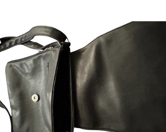 Open black leather shoulder bag with magnetic snap closure on a black background