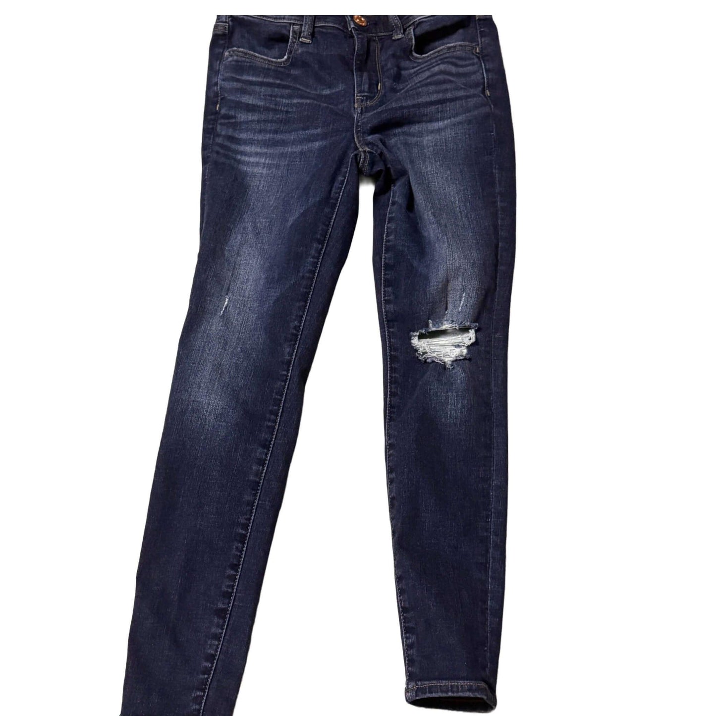 Dark wash distressed skinny jeans with ripped knee and faded details on white background