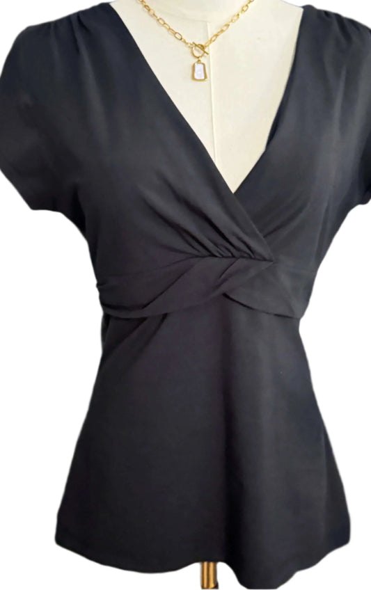 Black short-sleeve V-neck wrap blouse on mannequin, gold necklace accessory