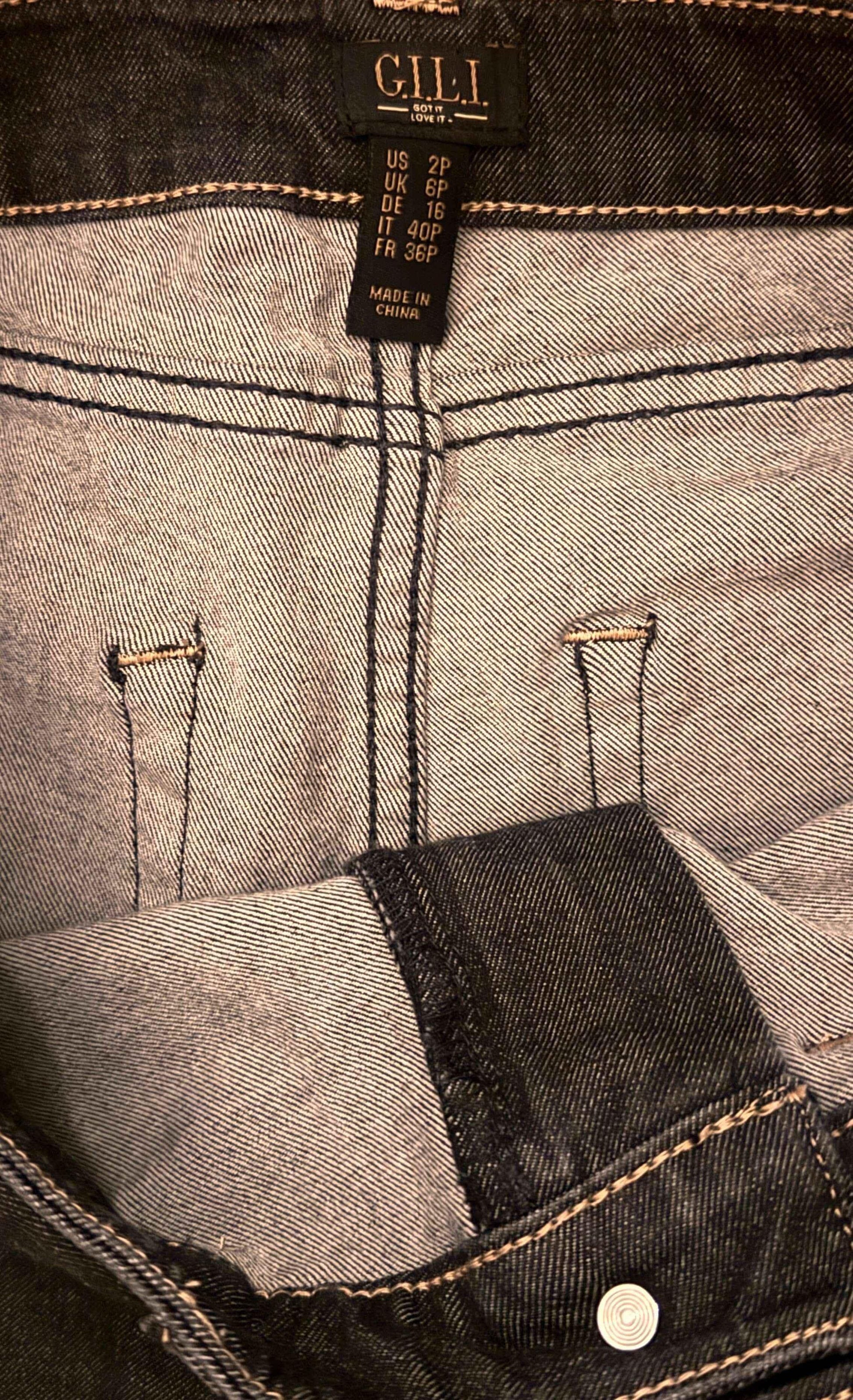 Close-up of G.I.L.I. black washed denim jeans waistband with size tag and stitching detail.