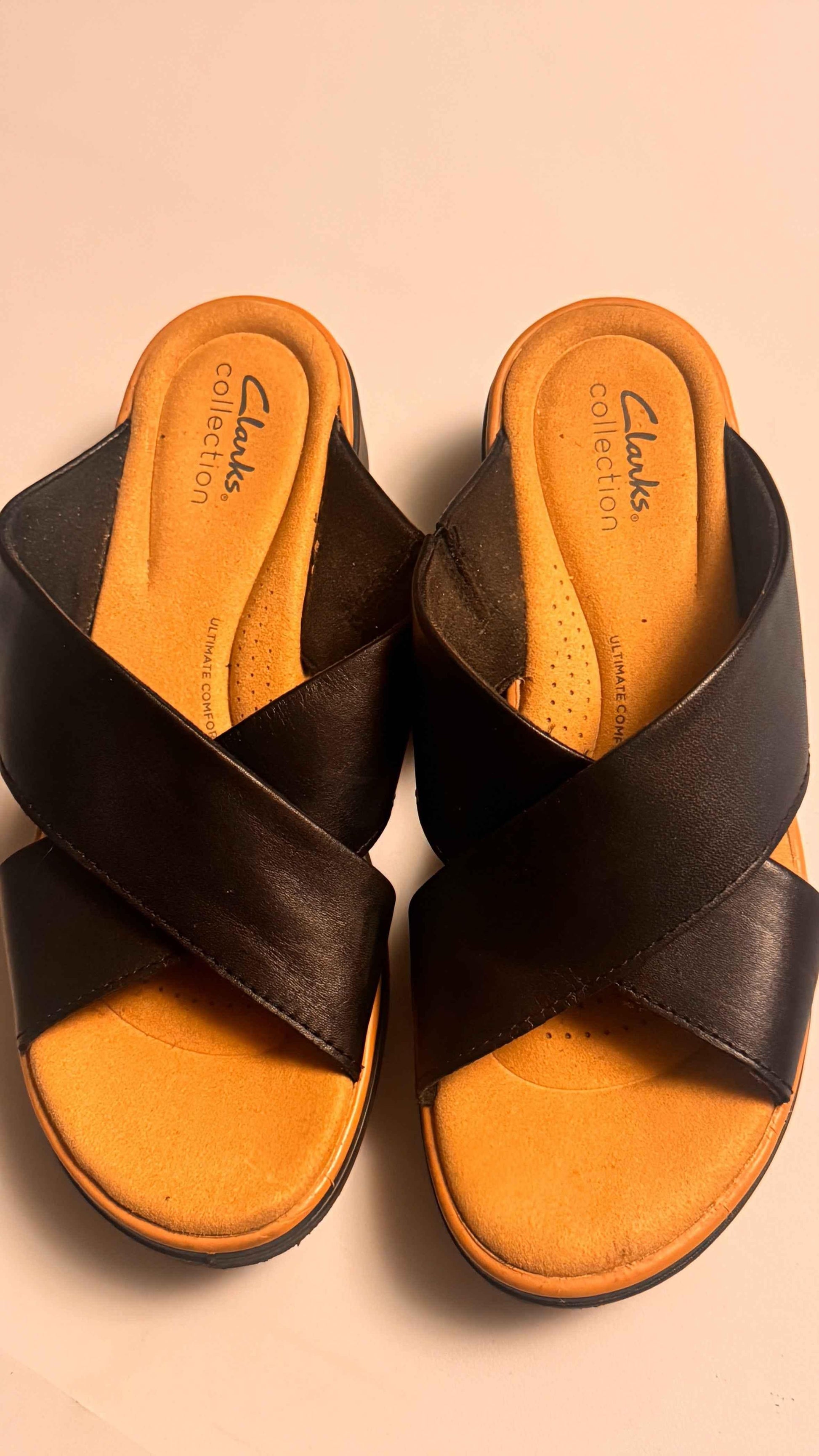 Clarks black leather slip-on sandals with tan cushioned insoles, top view.