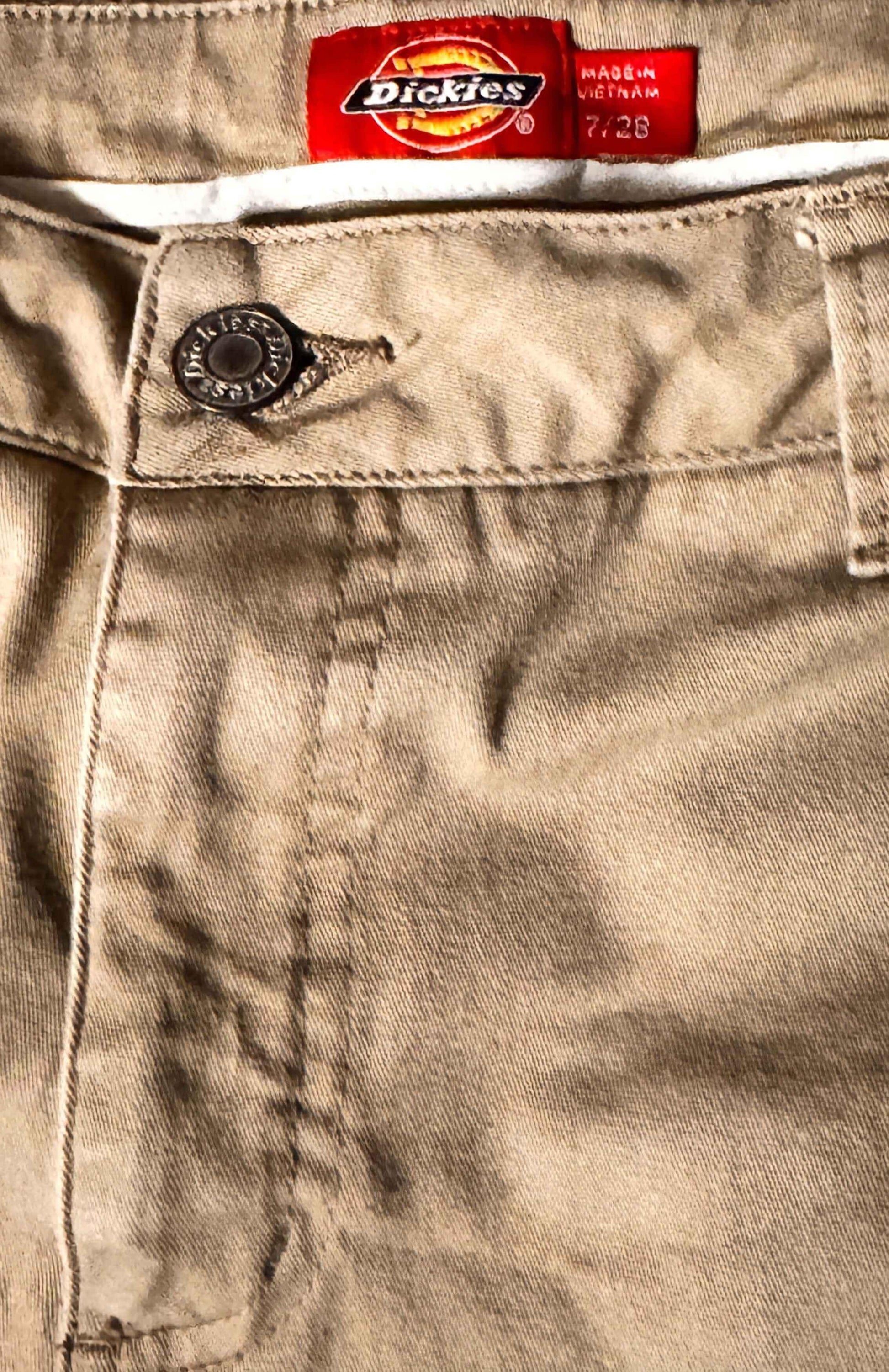 Close-up of tan Dickies pants waistband with branded tag and metal button