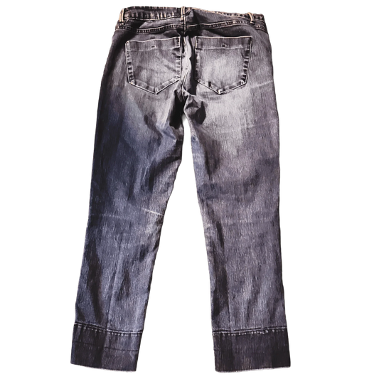 Back view of faded black denim jeans with two rear pockets on green background