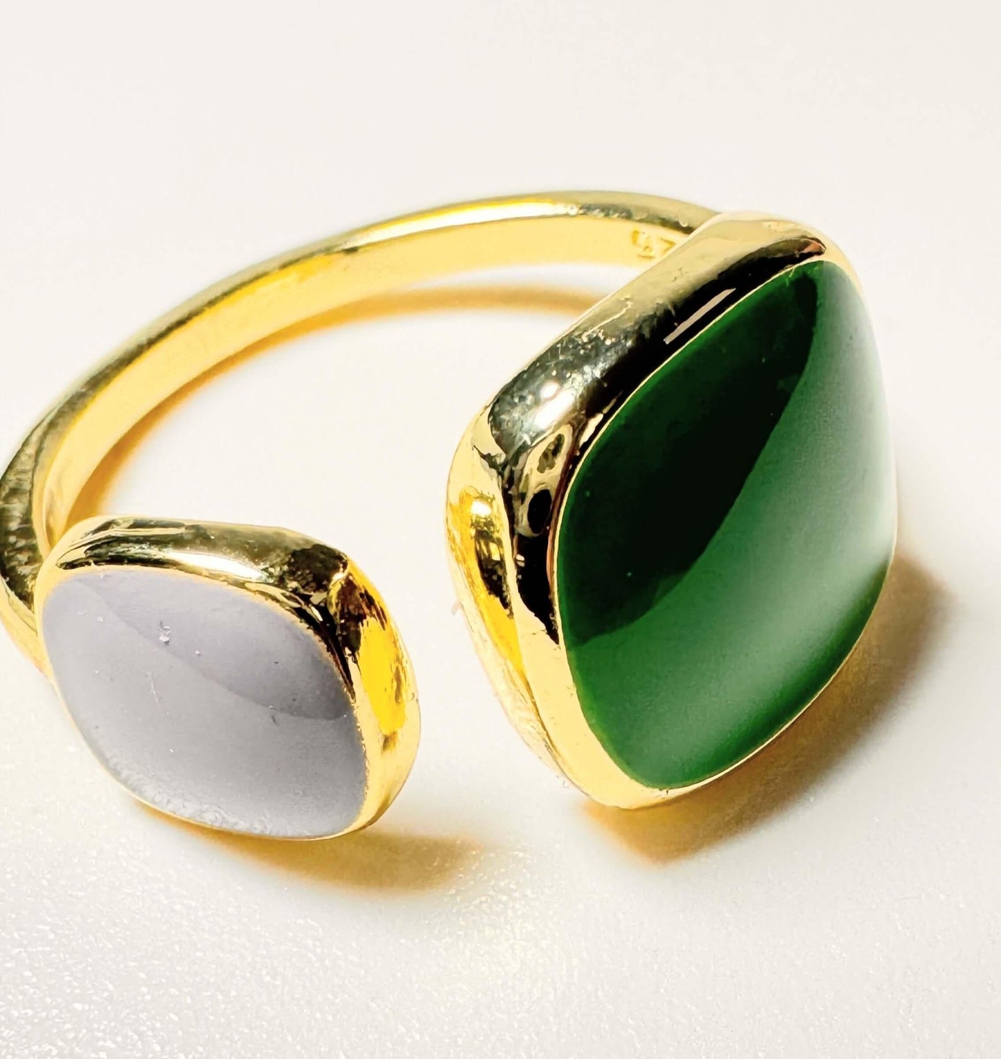 Gold ring with emerald green and gray stones on a white background