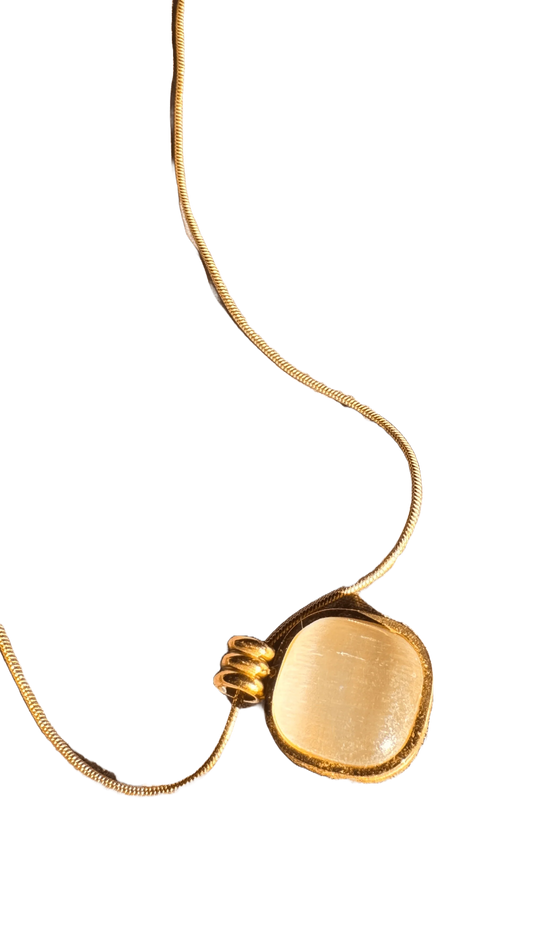 Gold necklace with square pendant on black background