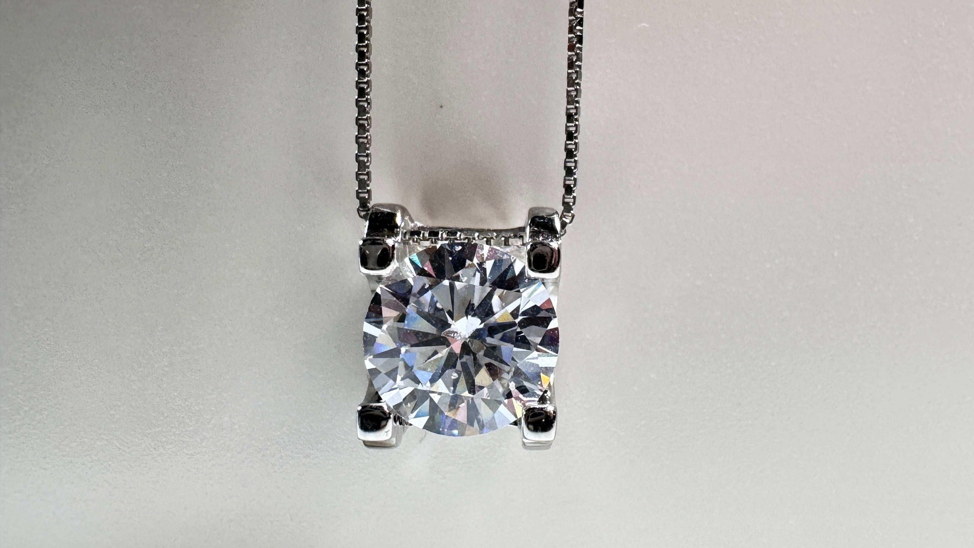 Lab grown diamond pendant on silver chain against light background