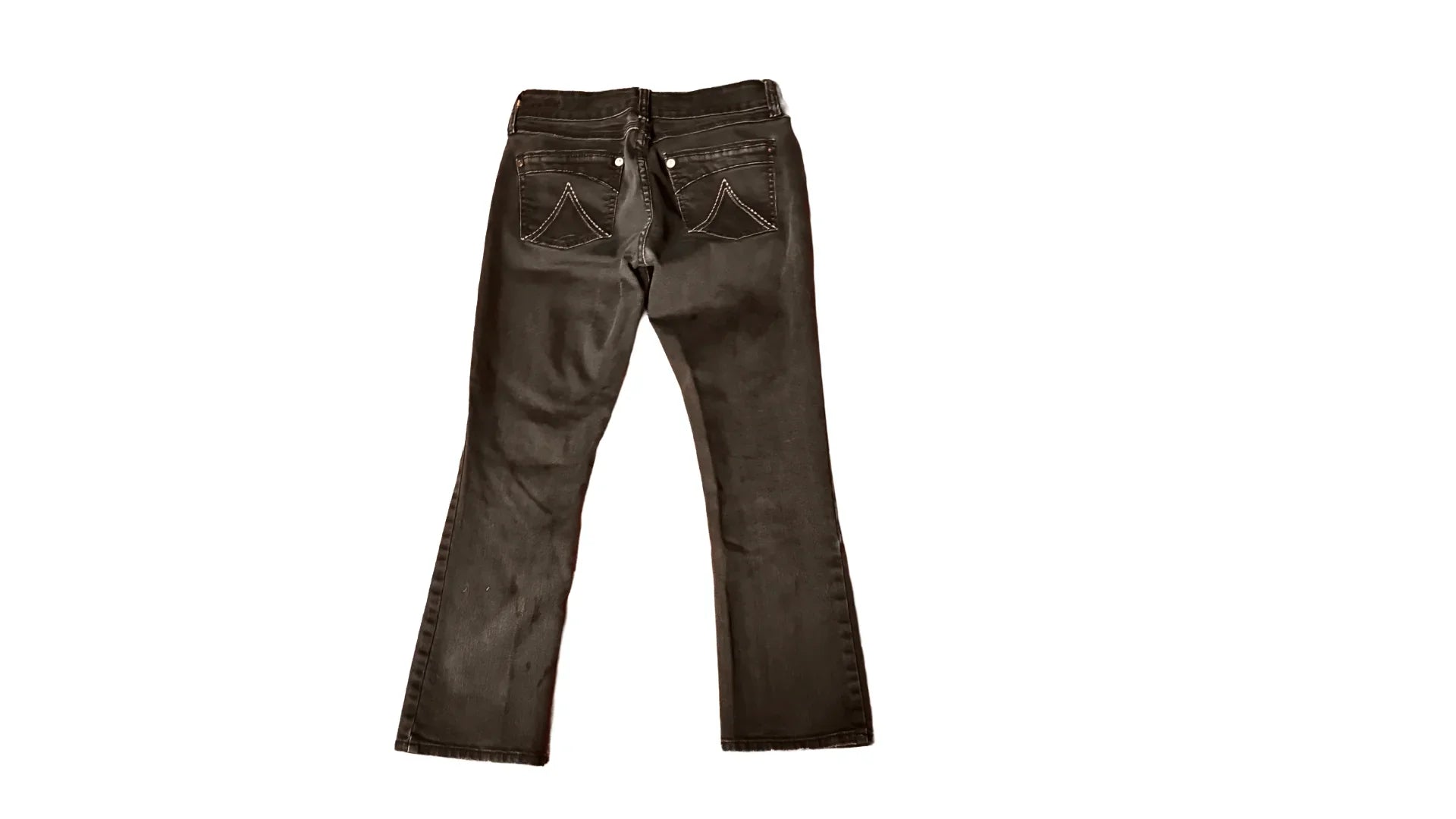 Black denim jeans with back pockets and white stitching on a white background