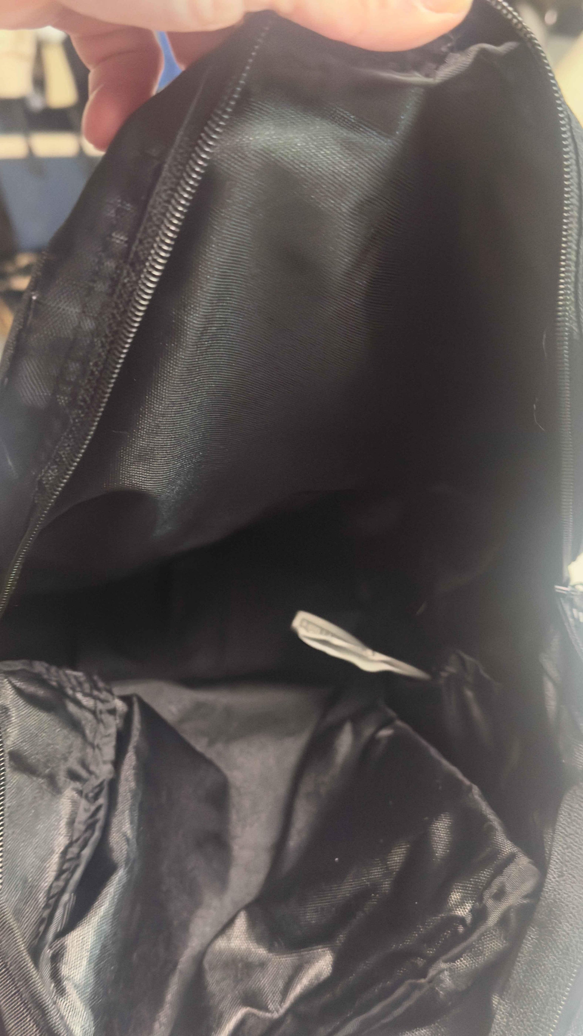 Open black Nike bag interior with zipper and fabric tag visible