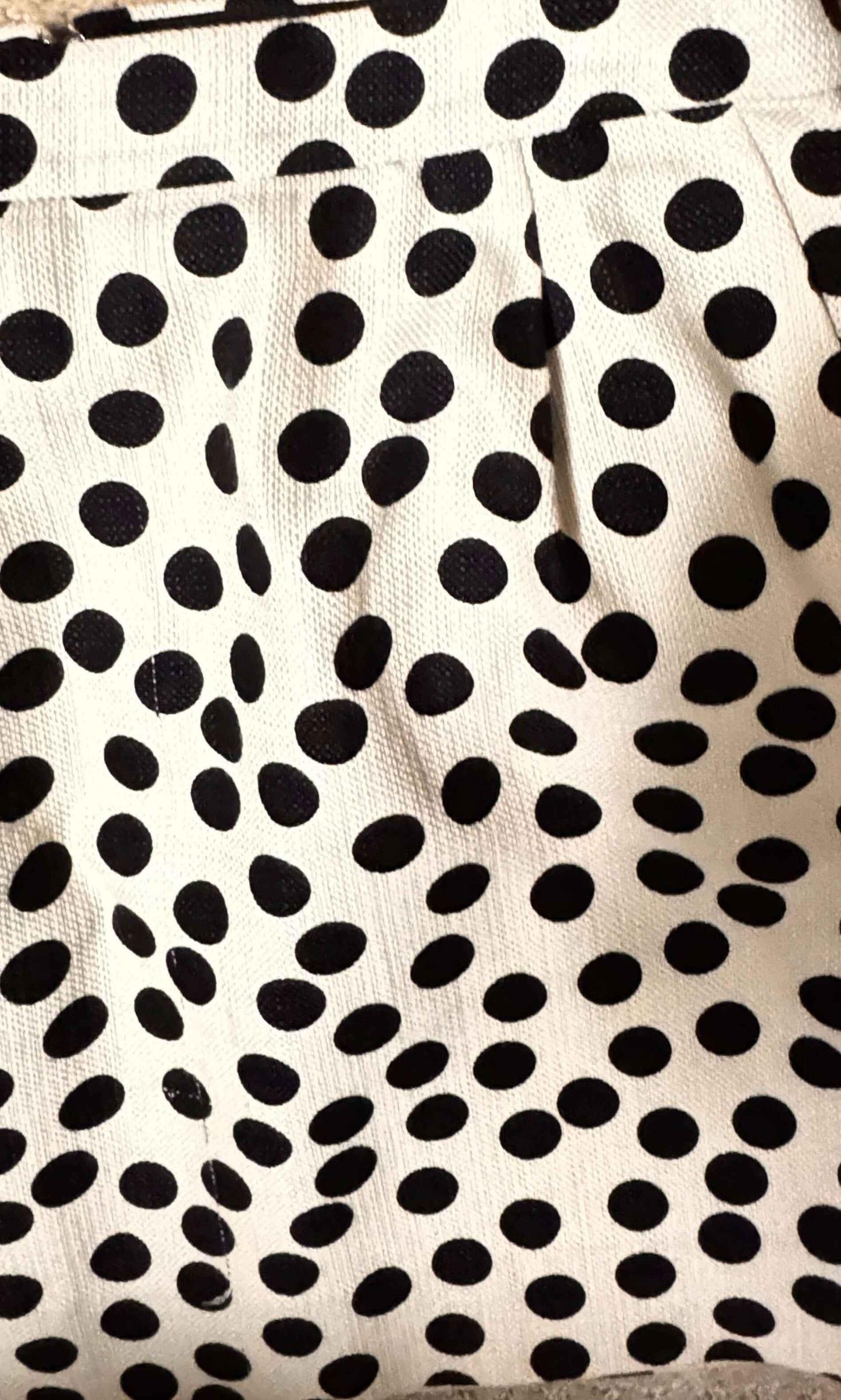 White skirt with black polka dots and pleats, close-up fabric texture