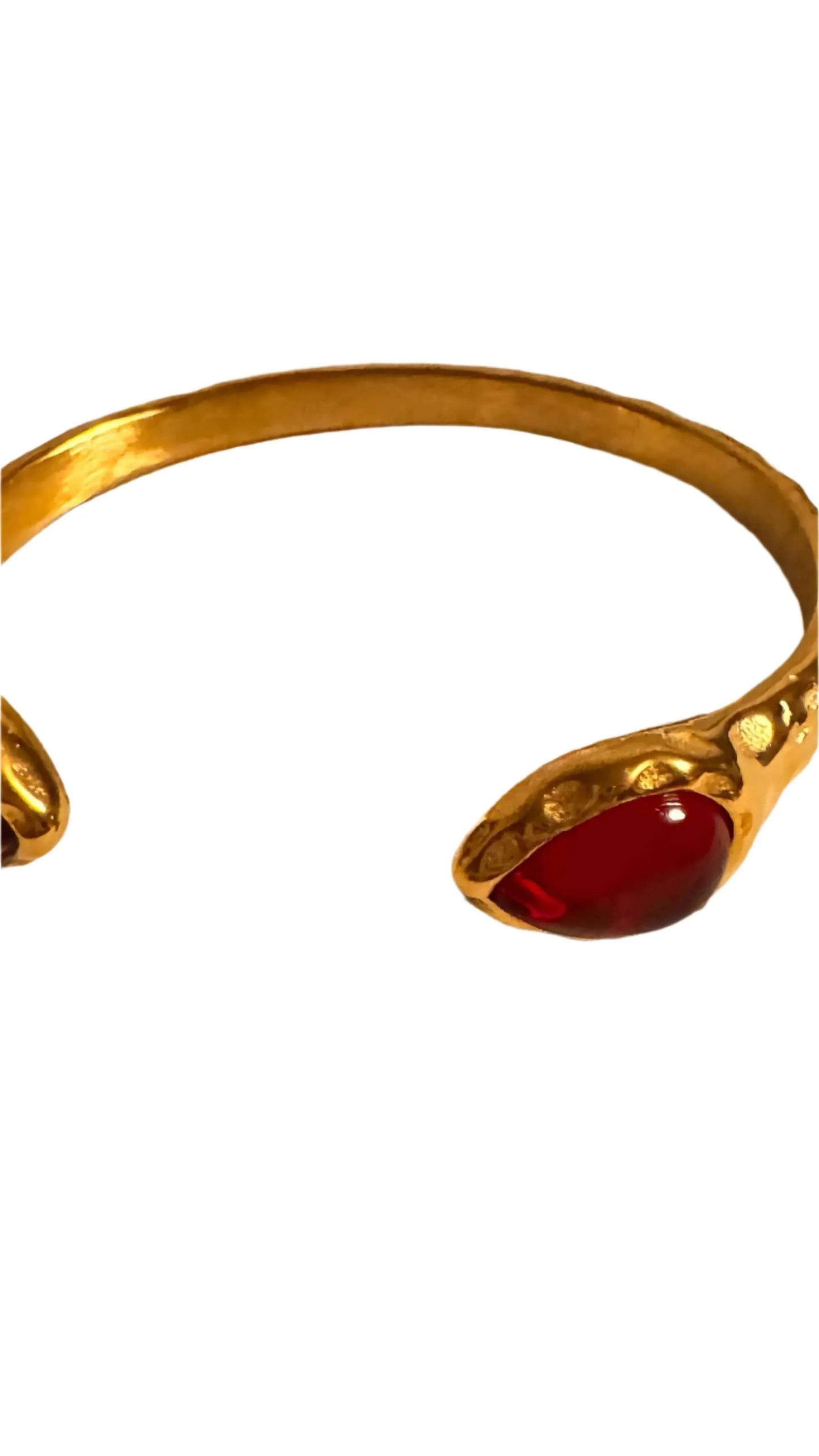 Gold band ring with red gemstone cabochon ends on white background