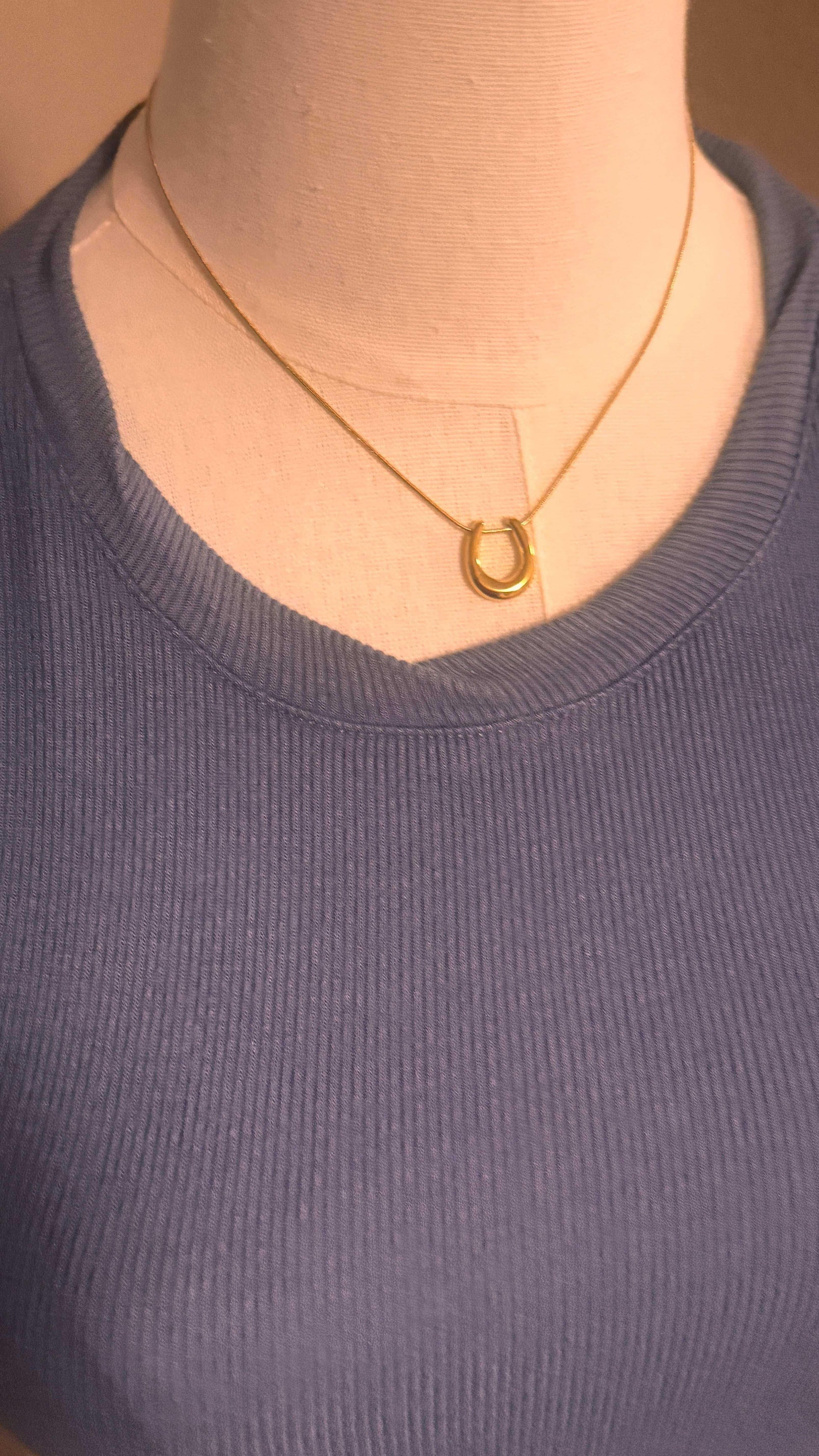 Close-up of blue ribbed snug-fit top on mannequin with gold horseshoe necklace
