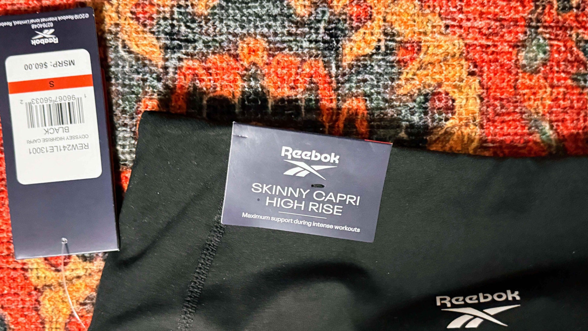 Reebok Skinny Capri High Rise black workout pants with tags on patterned fabric background