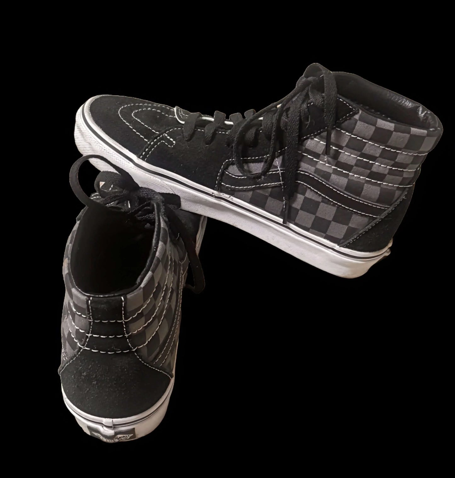 Vans high-top sneakers with black and gray checkerboard pattern on black background